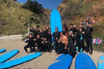 A group of surfers posing on a beach in Santa Cruz, CA